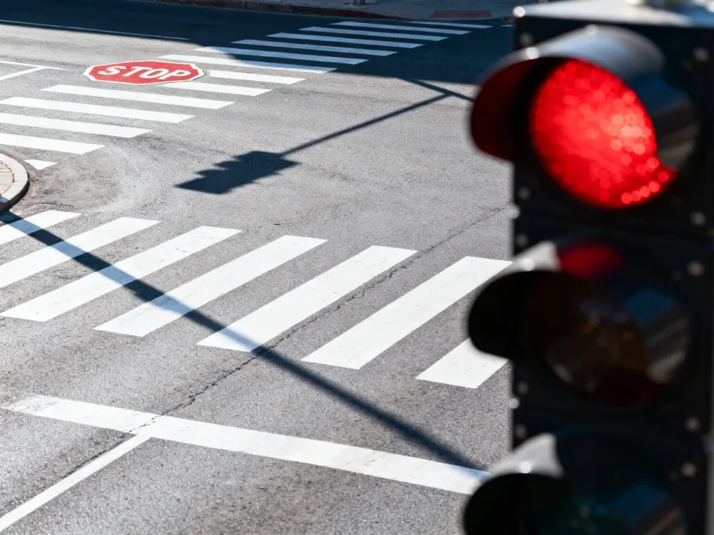 Skrzyżowanie z sygnalizacją świetlną pokazującą czerwone światło oraz znakiem stopu na drodze.